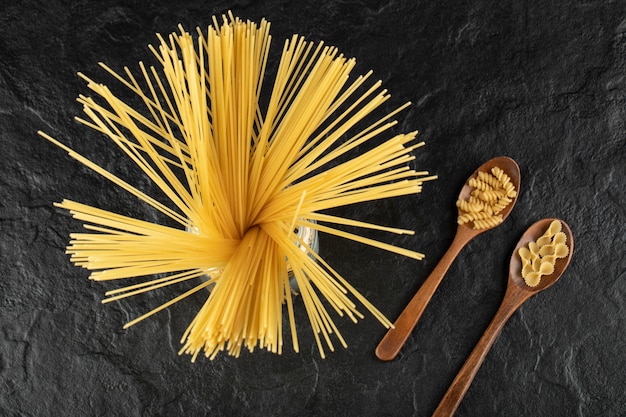 Foto gratuita tre tipi di pasta cruda su un tavolo nero.