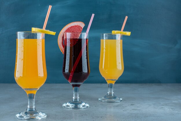 Three various juices in glass cups with straw. 