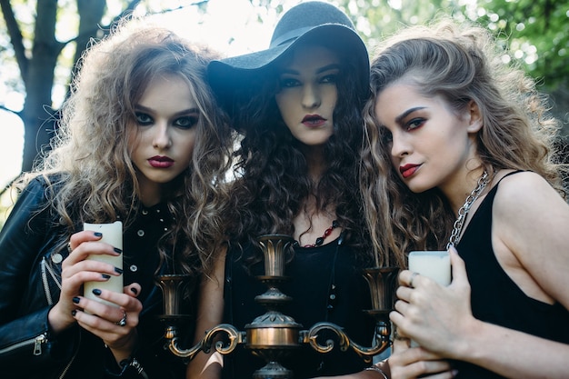 Three vintage women as witches, pose in front of an abandoned building on the eve of Halloween