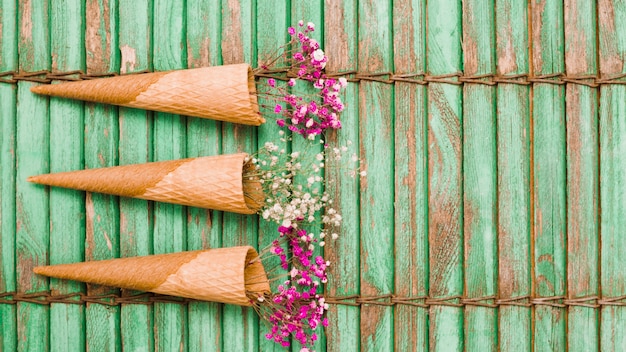 Free photo three waffle cone with baby's-breath flowers on wooden background