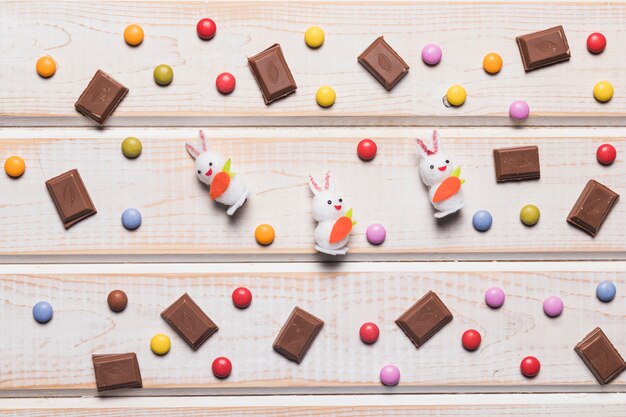 책상 위에 여러 가지 보석과 초콜릿 조각으로 둘러싸인 3 개의 흰 토끼