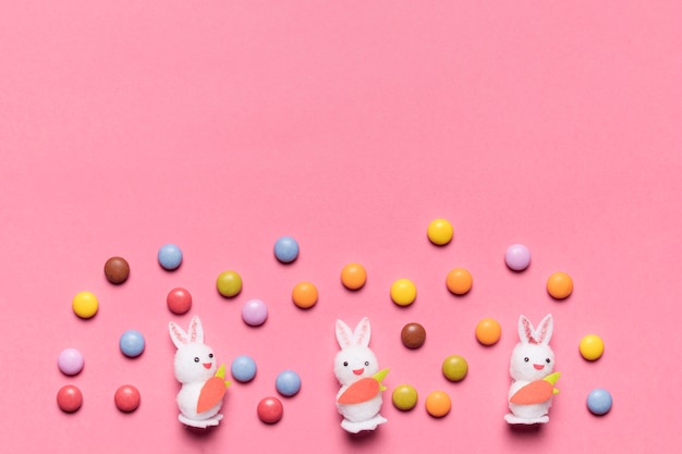 분홍색 배경에 화려한 보석 사탕과 3 개의 흰 토끼