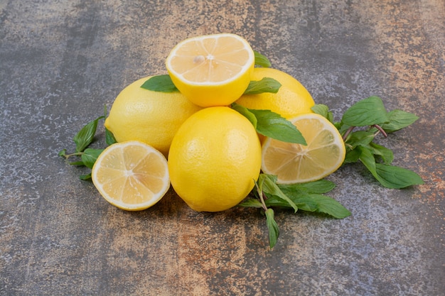 Foto gratuita tre limoni freschi interi con fetta su spazio in marmo