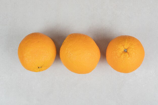 Three whole oranges on gray surface