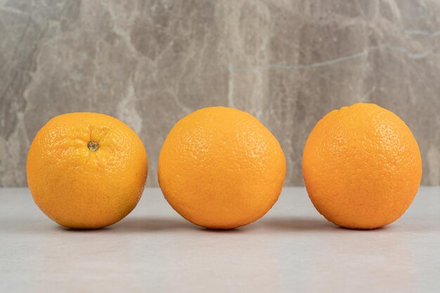 Три целых апельсина на сером столе
