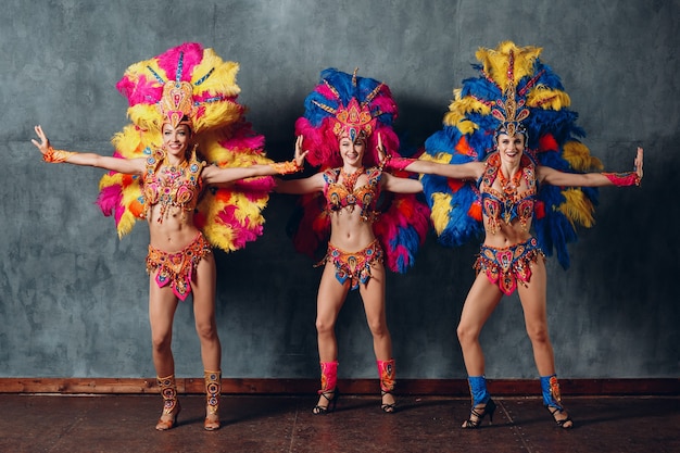 Three woman in brazilian samba carnival costume with colorful feathers plumage