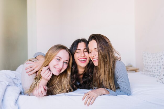 Three women hugging on bed