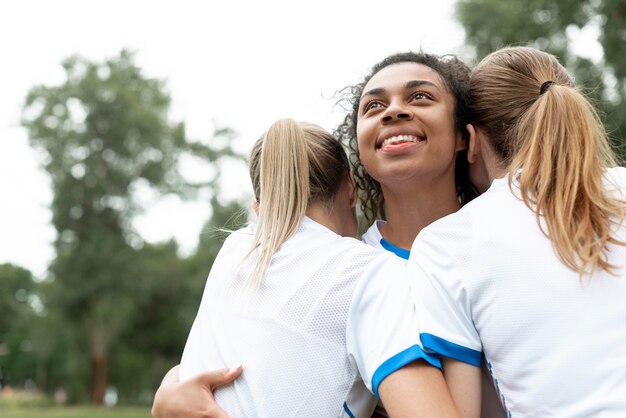 Three women hugging low angle