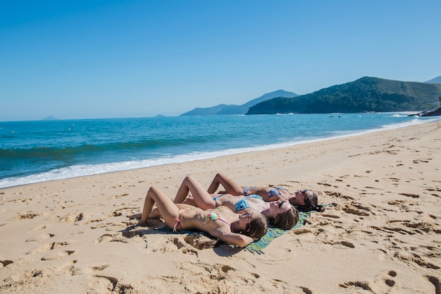 Foto gratuita tre donne che si trovano sulla spiaggia