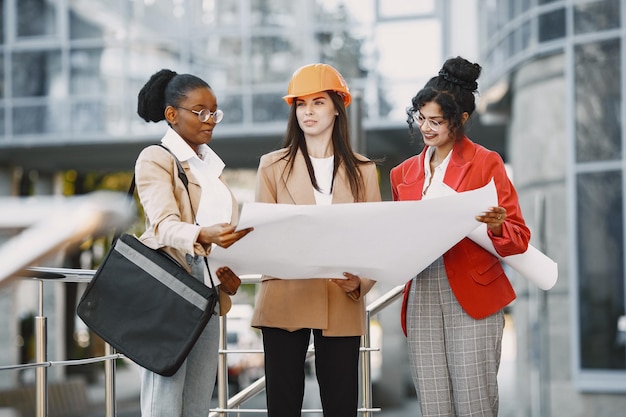 Three women working as architectors on a constraction and making a decision about plan of a building