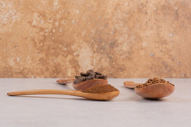 Three wooden spoons full of coffee beans and cacao powder. High quality photo