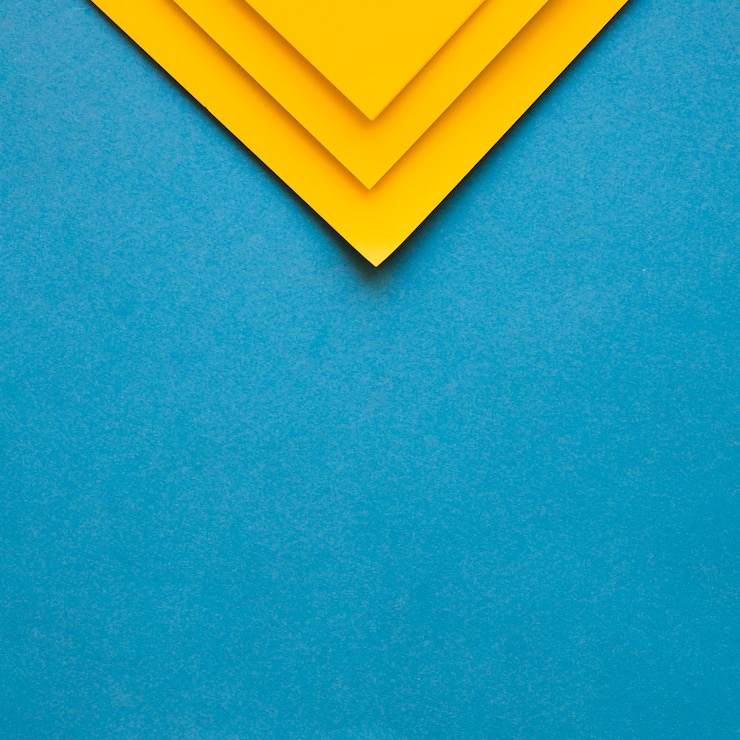 Free Photo three yellow cardboard papers at the top of blue backdrop