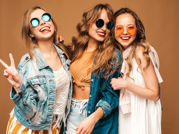 Three young beautiful smiling girls in trendy summer casual jeans clothes. Sexy carefree women posing. Positive models in sunglasses
