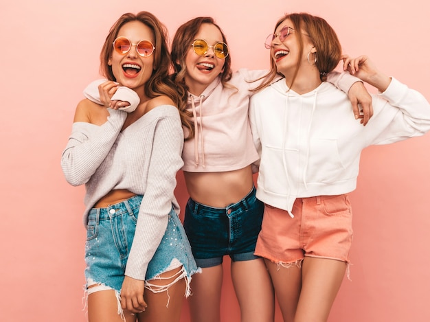 Три молодые красивые улыбающиеся девушки в модной летней одежде. Сексуальные беззаботные женщины позируют. Веселые позитивные модели