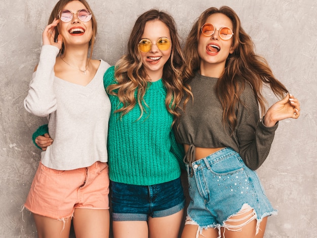 Free photo three young beautiful smiling gorgeous girls in trendy summer clothes.  sexy carefree women posing. positive models having fun in round sunglasses