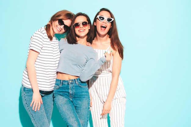 Three young beautiful smiling hipster female in trendy same summer clothes