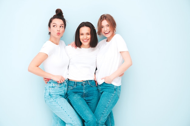 トレンディな同じ夏の白いTシャツとジーンズの服を着た3人の若い美しい笑顔の流行に敏感な女性