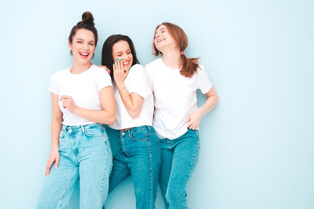 トレンディな同じ夏の白いTシャツとジーンズの服を着た3人の若い美しい笑顔の流行に敏感な女性