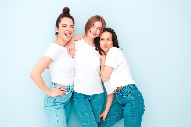 トレンディな同じ夏の白いTシャツとジーンズの服を着た3人の若い美しい笑顔の流行に敏感な女性