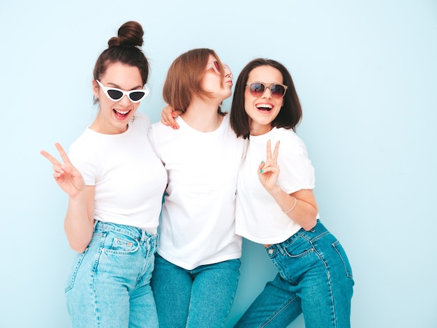 Three young beautiful smiling hipster female in trendy same summer white t-shirt and jeans clothes