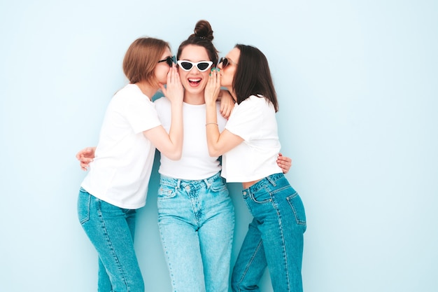 Three young beautiful smiling hipster female in trendy same summer white t-shirt and jeans clothes