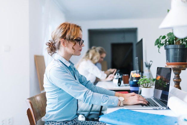 Three young businesswomen sitting at workplace talking to each other in the office