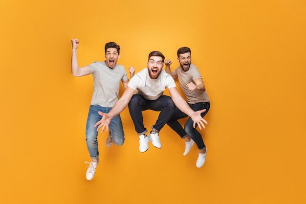 Three young excited men jumping together