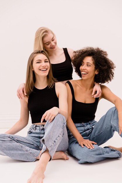 Three young interracial women in casual clothes laugh spending time together on white background Diverse ethnicity lifestyle