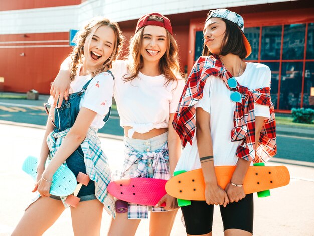 Free photo three young smiling beautiful girls with colorful penny skateboards.