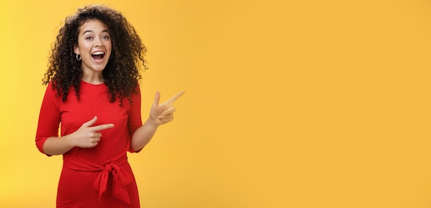 Free photo thrilled and happy joyful young charismatic woman with curly hair in red dress laughing out loud and