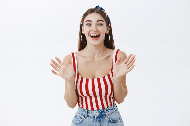 Thrilled sociable and talkative upbeat woman in striped trendy top with awesome body shaking palms joyfully and smiling surprised and excited