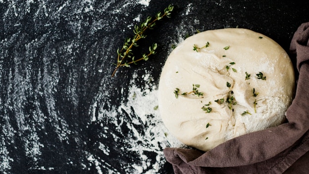 Thyme on kneaded raw dough over black kitchen worktop