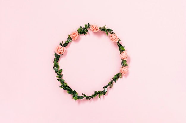 Тиара из искусственных роз и листьев на розовом фоне