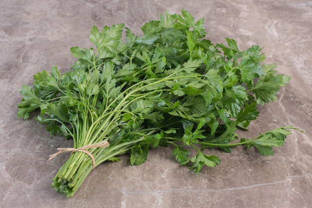 Tied bundle of parsley on marble surface