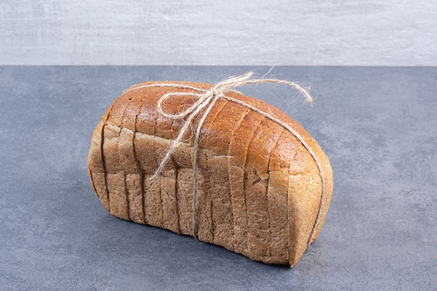 Tied-up block of sliced bread on marble.