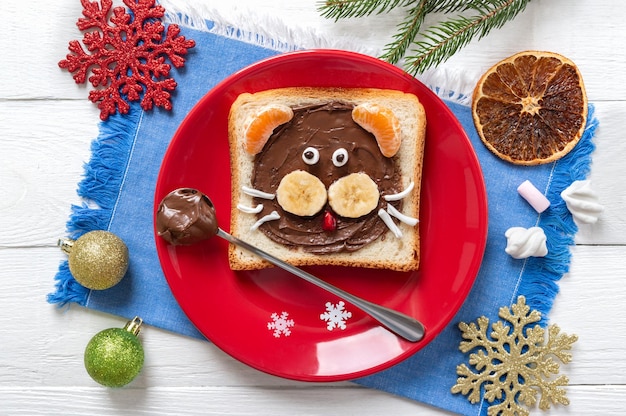 Сэндвич с головой тигра с шоколадом, бананом, мандарином и зефиром на тарелке на синей салфетке. праздничный завтрак для детей. вид сверху.