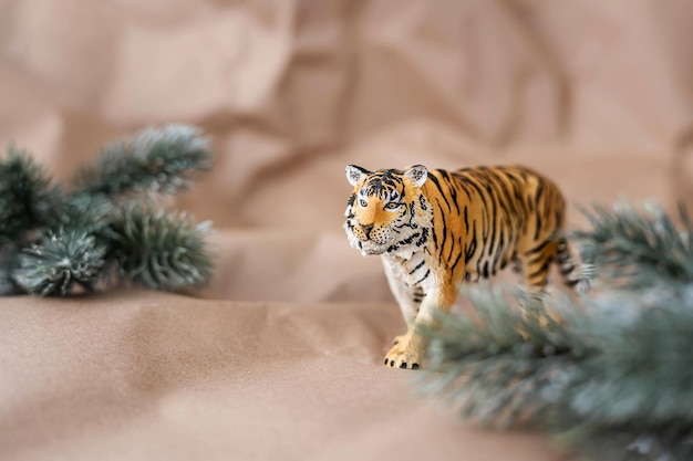 Tiger symbol of the chinese new year 2022. figurine of tiger with branches spruce tree on pastel background. copy space.