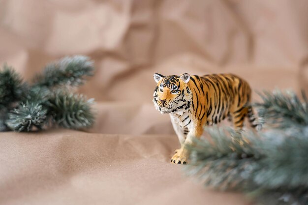 Tiger symbol of the chinese new year 2022. figurine of tiger with branches spruce tree on pastel background. copy space.