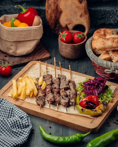 Foto gratuita kebab di tikka servito con patatine fritte e insalata verde