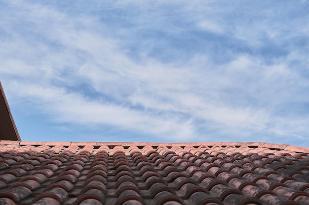 Free photo tiled roof against a blue sky with clouds an idea for a background with space for text ecofriendly traditional roofs for the home