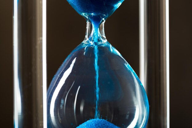 Time is passing. Blue hourglass close up