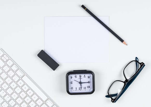 Time management concept with clock, pencil, eraser, eyeglasses, paper, keyboard on white background space for text, top view. horizontal image