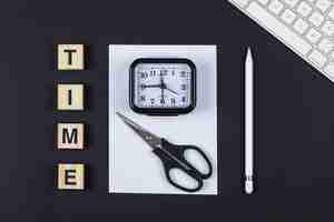 Free photo time management concept with wooden blocks, scissors, clock, pencil, paper, keyboard on black background top view. horizontal image