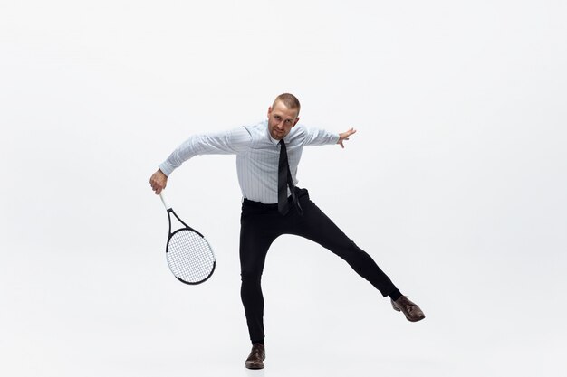 Time for movement. Man in office clothes plays tennis isolated on white. Businessman training in motion, action. Unusual look for sportsman, new activity. Sport, healthy lifestyle.