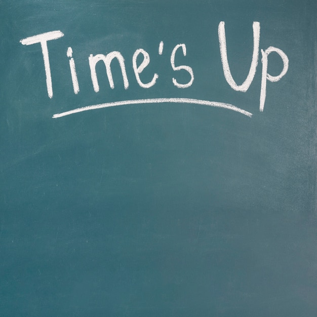 Times up written on green blackboard with chalk