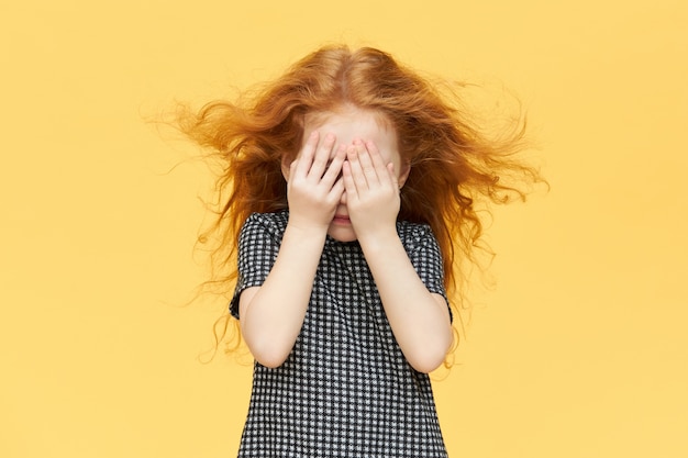 Timid little girl being shy, covering eyes