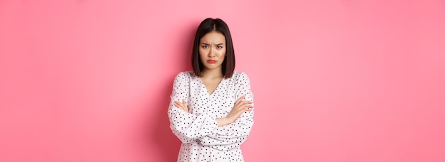 Free photo timid and offended asian girl cross arms on chest staring defensive and insulted at camera standing