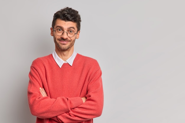 Free photo timid satisfied european man crosses hands over chest