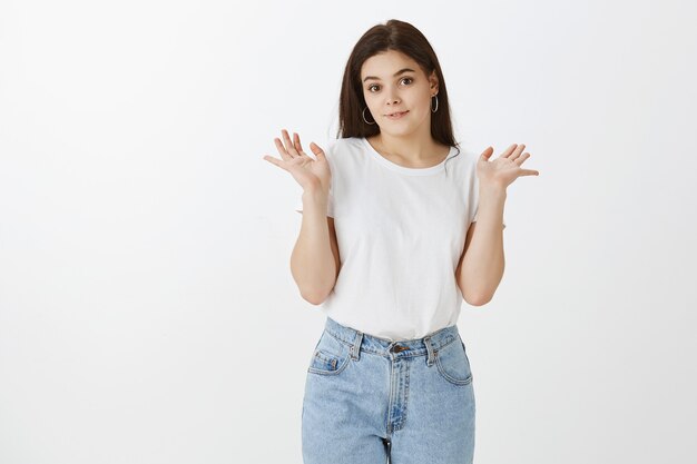 timid young woman posing against white wall