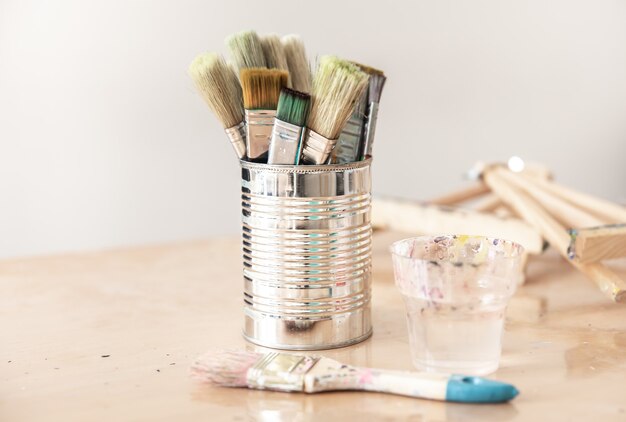 Tin can with paint brushes on a workshop table on a blurred background